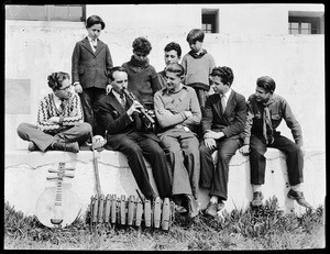 Group of children seated around a man playing a woodwind instrument