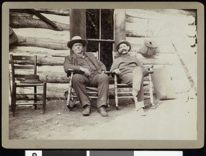 Two fishing club members sitting outside a mountain residence, ca.1910-1920