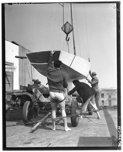 Three men lowering a rowboat onto a trailer