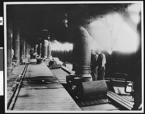 Workers inside a building supplying refrigeration to freight cars, ca.1920