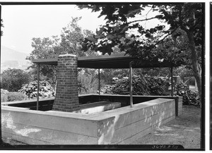 Outdoor stove with brick chimney at picnic grounds or campsite, showing large wood pile