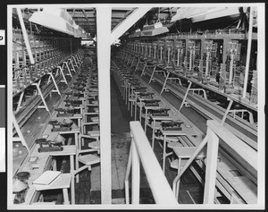 Unidentified factory conveyor belts, showing workers at the left back, ca.1950