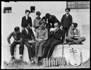 Group of children seated around a man holding a large seashell