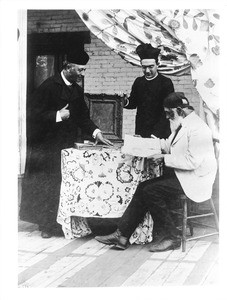 Two Los Angeles Plaza church priests with Don Antonio Coronel examining church records, ca.1885-1900