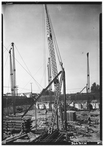 Cranes moving metal girders into place at a construction site