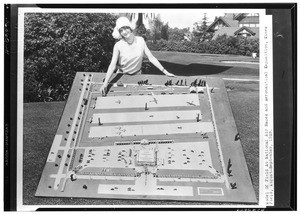 Young woman posing with model of aviation field for National Air Races, 1928