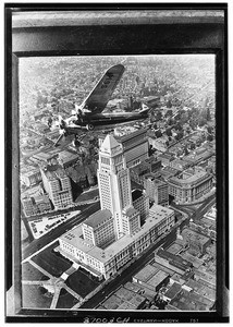 Fokker Tri-motor airplane flying over Los Angeles City Hall, 1929
