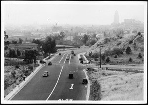 View of the completed lanes of North Figueroa Street, looking south, showing automobile traffic and pedestrians, ca.1936