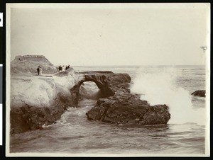 View of people standing by Arch Rock in Santa Cruz, ca.1900