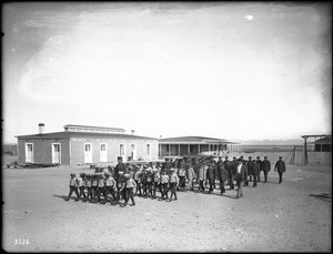 Group of Yuma Indian boys marching in front of the Indian School at Yuma, ca.1900