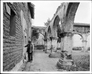 Don Pedro Verugo (a caretaker?) examining "the door to Father Serra's church" at the Mission San Juan Capistrano, Orange County, 1885