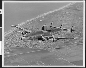 U.S. Air Force ECW-121 Warning Star plane in flight over a city, ca.1950