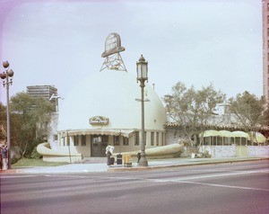 Exterior view of the original Brown Derby Restaurant, located at Wilshire Boulevard and Alexandria Street, showing yellow umbrellas on its terrace