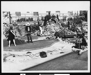 A woman putting at a miniature golf course, ca.1930