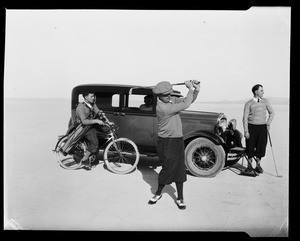 Golfer taking a swing near an automobile