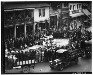 Large crowd gathered around a Chinese dragon costume in a demonstration on the streets of Chinatown, ca.1920-1929