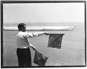 Man signaling with flags at the Marine Exchange, San Pedro, July 1931