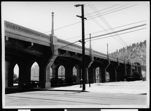 Concrete viaduct over a street, showing automobiles below the viaduct