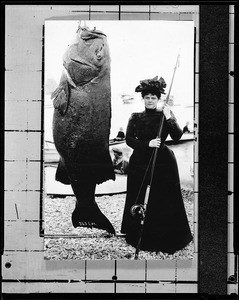 Portrait of a woman standing near a giant sea bass, 1930-1940