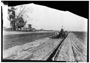 Man on a horse-drawn cart traversing the street work on Manchester Avenue, just west of Alameda Street and south of the New Firestone Plant site, 1927