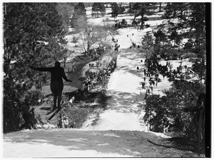 Ski jumper jumping down a mountain slope while a crowd watches