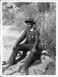 Havasupai Indian policeman, Lanoman, sitting on a blanket, ca.1900