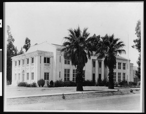 Exterior view of an unknown school showing two palm trees in front