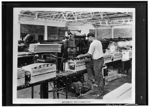 Man nailing down a crate with a nailing machine, ca.1925