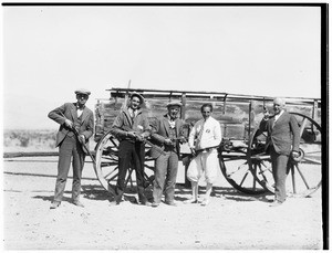 Five men posed in front of a wagon holding guns