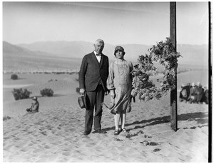 Couple standing next to a cross at a funeral in the desert