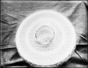 Indian basket displayed in front of a cloth backdrop, ca.1900