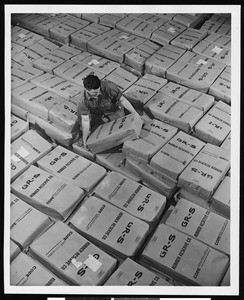 Worker moving packages of rubber product, ca.1945