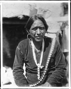 Navajo Indian man wearing large silver earrings, and wampum necklace, ca.1901