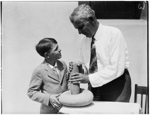 Man and boy using a Native American grinding stone at the Pacific Southwest Museum