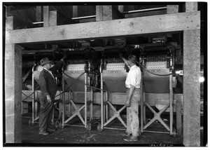 Men attending to machinery at a La Puente Valley Walnut Growers' Association packing house, 1927