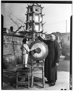 Young Japanese girl hitting a gong held by a monk