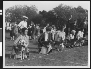 Women holding dogs at the start of race, ca.1930