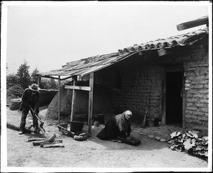 An older couple outside the "Hacienda Aguilar", at San Juan Capistrano Mission, Orange County, ca.1885