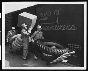 Three workers unloading tires from a rail car, ca.1950