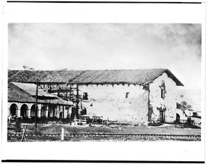 Exterior view of the Mission San Miguel showing railroad tracks in front, ca.1900