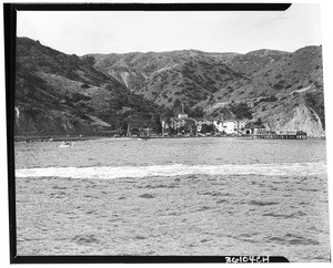 View of beach at Catalina Island, resort(?), pier and boats in the water