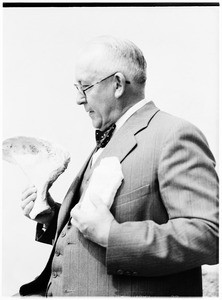 Man holding what appears to be pieces of bone at the Pacific Southwest Museum