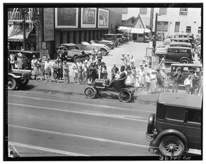 Line of people looking at two men in a small automobile