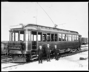 Three men standing in front of Pacific Electric car number four hundred eighteen in Long Beach, 1908