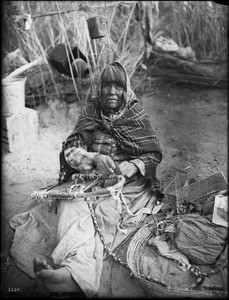 Chemehuevi Indian woman repairing a papoose basket, ca.1900