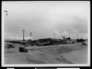 Automobile and steam shovels at work on a project in sand dunes