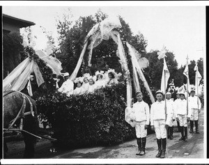 Formation of young boys standing near a horse-drawn float in the Pasadena Tournament of Roses Parade, ca.1905