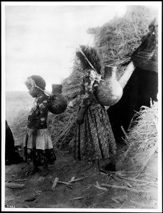 Two young barefoot Mission Indian girls carrying ollas, United States or South America