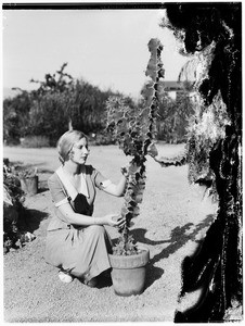 Woman crouched next to a cactus at the Natural History Museum