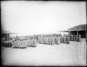 Ranks of Yuma Indian boys and girls posed between two buildings of the government Indian School at Yuma, ca.1900